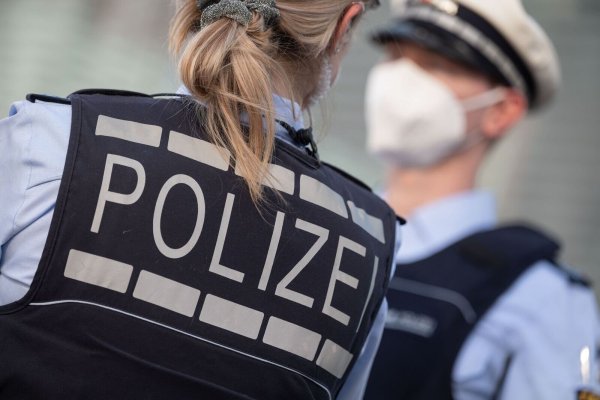 Eine Polizistin und ein Polizist mit FFP2-Maske stehen sich gegenüber. - © Marijan Murat/dpa/ZB