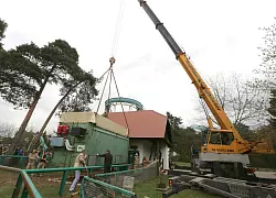 Der Kran platziert den Spezialcontainer genau vor der Stallt&uuml;r. Mehrere M&auml;nner helfen dabei.