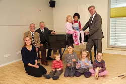 Sind zufrieden: Hochschulrektor Prof. Martin Christian Vogel (am Flügel), Dr. Burghard Lehmann von der Familie-Osthushenrich-Stiftung (links daneben) und Friedel Heuwinkel von der Stiftung Standortsicherung (rechts) freuen sich mit Musikpädagogin Birgit Herwig und einigen Kindern über den guten Start des Musikkindergartens. - © Foto: Beckmann