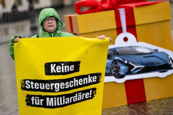 Eine Greenpeace-Aktivistin auf einem Protest für eine Milliardärssteuer am Brandenburger Tor. - © Fabian Sommer/dpa