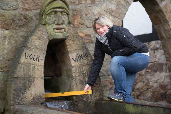 Denise Friedrich von der Tourist-Info prüft zum Spaß das märchenhafte und „bergauf laufende" Stadtwasser in Schwalenberg. Um sich die kleine Geschichte zu erhalten, sollten Besucher die Wasserwaage allerdings nicht zu genau anlegen. - © Foto: Torben Gocke