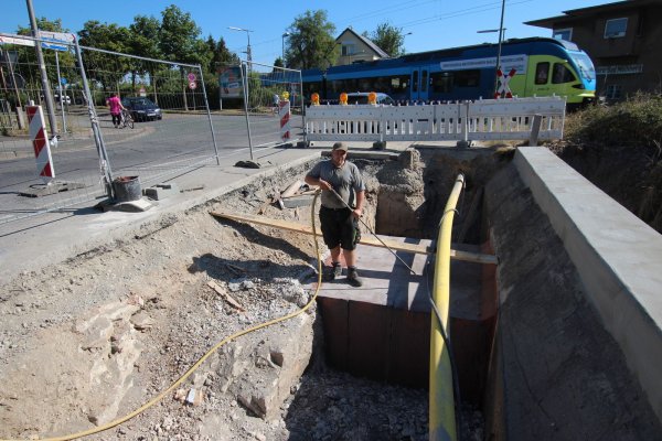 In der Baugrube: Michael Schoppmeier beseitigt mit Druckluft Dreck und Staub von dem aus Fertigbauteilen bestehenden Kasten durch den das Wasser des Stadtgrabens verläuft. Im Hintergrund überquert gerade ein Zug den Bahnübergang in Horn. - © Patrick Bockwinkel(LZ)