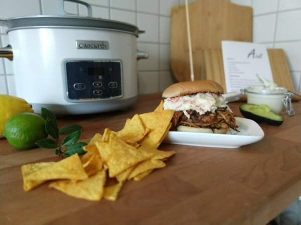 Üppig beladen: Nach 20 Stunden kommt das Fleisch für "Pulled Pork" aus dem Slow-Cooker, wird zerrupft und auf einem Burgerbrötchen angerichtet. Dazu passen Krautsalat, Nacho-Chips und ein Dip. - © Yvonne Glandien