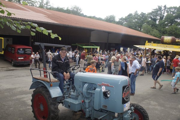 Bernhard Fasse aus Asendorf ist stolz auf seinen Trecker-Oldtimer von 1957. Er und viele weitere Aktive, Vereine und Direktvermarkter (im Hintergrund) freuen sich über den Andrang beim „Schwoof auf dem Hof". - © Werner Hoppe