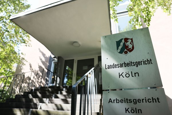 Das Logo des Landesarbeitsgerichts und des Arbeitsgerichts in Köln hängen am Eingang zum Gebäude. - © Oliver Berg/dpa
