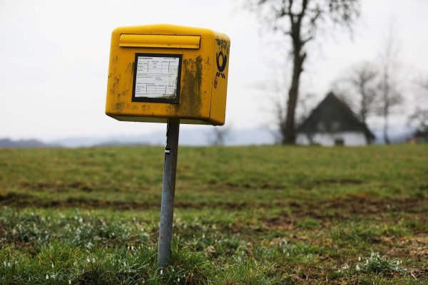 Ein Briefkasten der Deutschen Post steht auf einer Wiese am Rand einer Siedlung im Bergischen Land (NRW). - © Oliver Berg/dpa