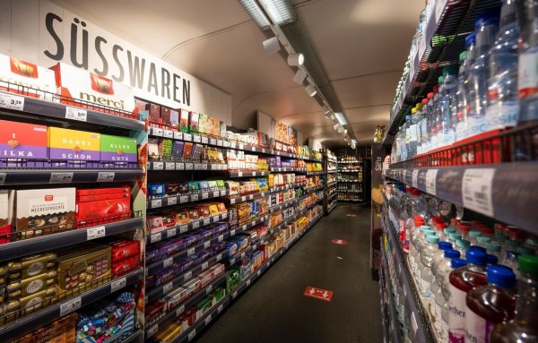 Diverse Lebensmittel stehen in Regalen in einem Einkaufszug. - © Monika Skolimowska/dpa