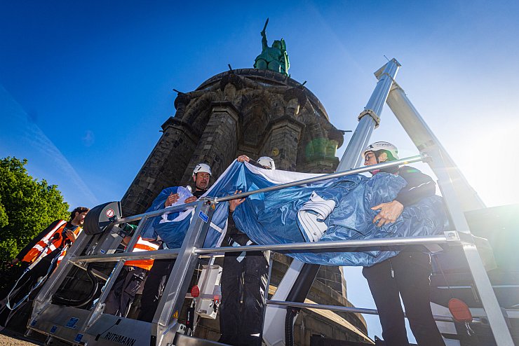Die Monteure André Brünger Steuermann, Jens Rosigkeit, Björn Strasas und Sigrid Prziwara bringen mit einer Hebebühne das XXXL-Arminia-Trikot an. - © Mike-Dennis Mller / www.mdm.photo