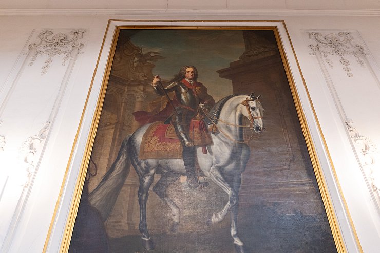 Dieses Gemälde, das in der barocken Winterreitschule hängt, zeigt Bauherrn Kaiser Karl VI. Noch heute würdigen die Reiter ihn, indem sie jedes Mal, wenn sie die Halle mit den Pferden betreten, ihre Zweispitze absetzen und Richtung Gemälde blicken. - © Niklas Tüns