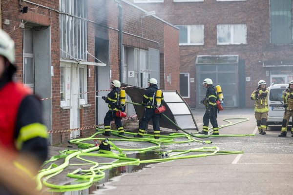 Feuerwehrleute bringen einen Brand in einer Lagerhalle in Köln unter Kontrolle. - © Thomas Banneyer/dpa