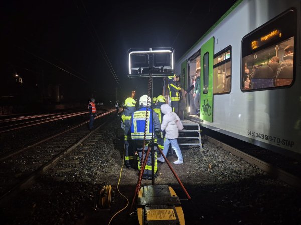 Feuerwehrleute helfen Reisenden, einen liegen gebliebenen Zug zu verlassen. - © Feuerwehr Schwelm/dpa