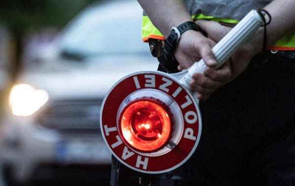 Ein Polizist hält bei einer Verkehrskontrolle eine Winkerkelle in der Hand. - © Paul Zinken/dpa/ZB/Symbolbild