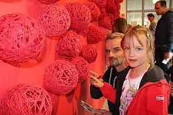 Kunst von Kindern: Die roten Fadennester des dritten Jahrgangs verschönern eine Wand im Neubau. Christian Müller und Elisa Müller (7) finden einen der drei versteckten Gegenstände. Ein weiterer ist ein Würfel. - © Karolina Schmidt