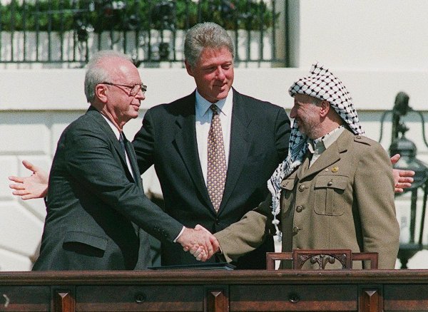 Ein Handschlag, der die Hoffnungen auf einen Frieden zwischen Israel und den Palästinensern symbolisiert: Der damalige Ministerpräsident von Israel, Izchak Rabin (l), und Jassir Arafat (r), damaliger Vorsitzender der Palästinensischen Befreiungsorganisation PLO, geben sich im Beisein von Ex-US-Präsident Bill Clinton die Hand. - © Avi Ohayon/Israeli Government Pr/EPA/dpa