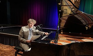 Sebastian Krämer bei der Hörbuch-Lesung: „Ein Licht geht uns auf…“ im Forum der Karla-Raveh-Gesamtschule Lemgo am Klavier. - Tamina-Shirin Marten