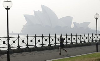 Ein Jogger l&auml;uft am Morgen, w&auml;hrend Rauchschleier &uuml;ber der Sydney Opera House h&auml;ngt. - Foto: Rick Rycroft/AP/dpa