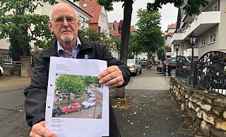 Michael Pfaff zeigt in der Freidenstraße ein Foto, was er gemacht hat und dass seine Parksituation in der kleinen Straße zeigt. Er fürchtet, dass die Feuerwehr im Ernstfall nicht mehr durchkommt. - Sven Kienscherf