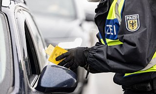 Ein deutscher Bundespolizist kontrolliert an der Grenze zu Österreich den Impfpass einer einreisenden Person. - Foto: Matthias Balk/dpa Ein deutscher Bundespolizist kontrolliert an der Grenze zu Österreich den Impfpass einer einreisenden Person. - Foto: Matthias Balk/dpa