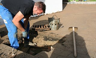 Aufräumarbeiten: Mark Jäger gräbt einen Kanal frei, der durch den Matsch verstopft ist. Sein ganzer Hof, der an Werkstatt und Tankstelle an der Extertalstraße grenzt, war vollgelaufen. - Kirsten Fuhrmann