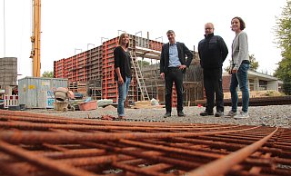Der Umbau läuft: (von links) Isabell Matejek, Tagesstättenleiterin bei „Das Dach", Ortsausschussvorsitzender Thorsten Sagner, Feuerwehrchef Klaus Wegener und Architektin Regine Schmelzer von der Stadt sehen sich den Stand an der alten Schule Hörstmar an. Im Hintergrund entsteht die neue  Fahrzeughalle für die Feuerwehr mit ihren hohen Toren. - Till Brand