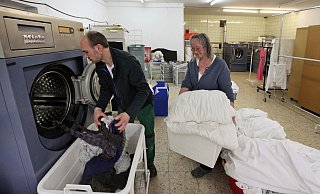 Der Betrieb am neuen Standort in der Saganer Straße läuft an. Wäschereileiter Stanislav Fuchs entleert eine Profiwaschmaschine, während Geschäftsführerin Marie-Luise Bolle schon den nächsten Korb Schmutzwäsche bereithält. - Bernhard Preuss Der Betrieb am neuen Standort in der Saganer Straße läuft an. Wäschereileiter Stanislav Fuchs entleert eine Profiwaschmaschine, während Geschäftsführerin Marie-Luise Bolle schon den nächsten Korb Schmutzwäsche bereithält. - Bernhard Preuss