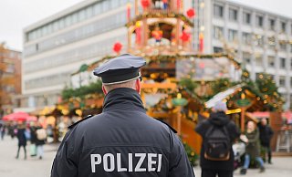 Ein Polizist steht auf einem Weihnachtsmarkt. - Julian Stratenschulte/dpa/Symbolbild Ein Polizist steht auf einem Weihnachtsmarkt. - Julian Stratenschulte/dpa/Symbolbild
