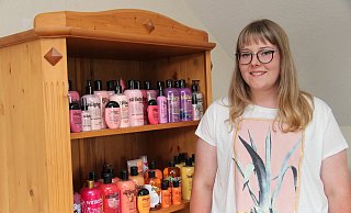 Lisa Ritter vor einem Teil ihrer bunten Duschgel-Sammlung, die farblich sortiert und somit dekorativ im Wohnzimmerschrank ihren Platz gefunden hat. - Nadine Uphoff