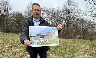 Nicolai Trettin zeigt das Bild eines Gebäudes auf dem Areal in der Nähe der AWO-Kita. Das Foto ist aber lediglich zur Illustration gedacht, wie ein Dorfgemeinschaftshaus einmal aussehen werde, müsse sich zeigen. - Sven Kienscherf Nicolai Trettin zeigt das Bild eines Gebäudes auf dem Areal in der Nähe der AWO-Kita. Das Foto ist aber lediglich zur Illustration gedacht, wie ein Dorfgemeinschaftshaus einmal aussehen werde, müsse sich zeigen. - Sven Kienscherf