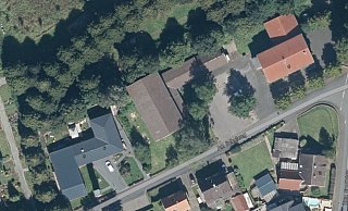 Die Stra&szlig;e "Am Schulweg" in Ahmsen aus der Vogelperspektive. Der neue Dorfplatz soll zwischen dem Dorfgemeinschaftshaus (rechts oben) und der Turnhalle (Bildmitte) entstehen. Hinter dem Dorfgemeinschaftshaus befindet sich weiterer Parkraum f&uuml;r Autos (ganz rechts). - TIM-online/Geobasisdaten NRW