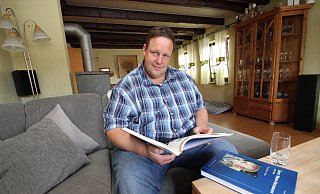 Ingo Mühlenmeier sitzt in seinem Wohnzimmer und blättert in der Dorfchronik von Günter Meier. Das Engagement im Dorf und in der Kalletaler Kommunalpolitik ist seit Jahrzehnten sein Ding.  - Jens Rademacher