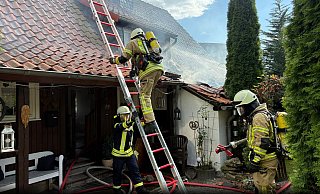 Rauch steigt auf: Feuerwehrleute tragen schweren Atemschutz, während sie das Feuer im Dach löschen. - Feuerwehr Bad Pyrmont Rauch steigt auf: Feuerwehrleute tragen schweren Atemschutz, während sie das Feuer im Dach löschen. - Feuerwehr Bad Pyrmont