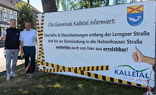 Gesch&auml;ftsinhaber Jannis R&ouml;themeier (links) und B&uuml;rgermeister Mario Hecker pr&uuml;sentieren das Banner vor dem Kalletaler Rathaus. - Gemeinde Kalletal