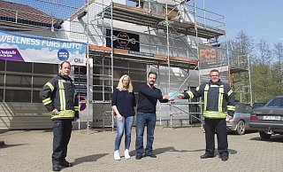 Übergabe der Tankgutscheine vor der Brandstelle über der Werkstatt: Löschzugführer Marcus Hermann, Merle und Holger Ehm sowie Gemeindebrandinspektor Michael Grüttemeier (von links). - Wulf Daneyko