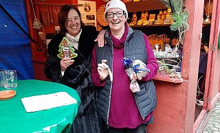 Regina Zelms (links, Kelter und Kultur Verein) und Margarida Pogarell (Autorin aus Portugal) zeigen  lokale Spezialitäten wie Bonbons, Fisch und Lebkuchen.  - Julia Kube