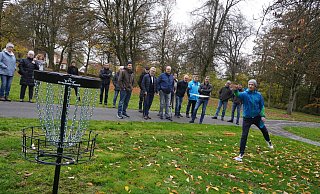 Wie funktioniert das eigentlich mit dem Discgolf? Das ließen sich die Lokalpolitiker am Samstag im Kurpark von Christoph Acktun erklären. Ziel ist, die Scheibe mit möglichst wenigen Würfen im Korb zu versenken. - Michaela Weiße