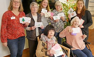 Ein weihnachtlicher Gruß für jeden: Die Bewohnerinnen freuen sich mit Hausleitung Sarah Köpel (rechts) und Melanie Beuke vom Begleitenden Dienst (links) über die viele Weihnachtspost der Schülerinnen und Schüler, die Lehrerin Nicole Burgard (hinten, Mitte) vorbeigebracht hat. - Fotorechte: Diakonis