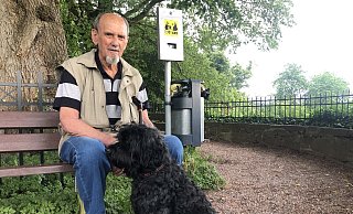 Horst Frunzke sitzt mit seinem Hund „Donald“ auf einer Bank, neben der ein Kotbeutel-Spender angebracht ist. - Silke Buhrmester