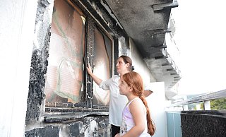 Nijazije Ejupiy, hier mit Tochter Suela (6) deutet auf den Brandschaden, der in der vergangenen Silvesternacht durch Unbekannte verursacht worden ist. Nach wie vor lebt die Familie mit verkohlten Fenstern und einem verkohlten Balkon. - Karin Prignitz Nijazije Ejupiy, hier mit Tochter Suela (6) deutet auf den Brandschaden, der in der vergangenen Silvesternacht durch Unbekannte verursacht worden ist. Nach wie vor lebt die Familie mit verkohlten Fenstern und einem verkohlten Balkon. - Karin Prignitz