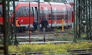 Mitarbeiter der Polizei stehen bei einem Zug auf dem Gelände des DB Betriebsbahnhofs Deutzer Feld. Hier wurde das verdächtige Paket in einem abgestellten Zug entdeckt. - Foto: Steil-TV/dpa Mitarbeiter der Polizei stehen bei einem Zug auf dem Gelände des DB Betriebsbahnhofs Deutzer Feld. Hier wurde das verdächtige Paket in einem abgestellten Zug entdeckt. - Foto: Steil-TV/dpa