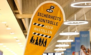 Eine Aufstell-Flagge weist Flugreisenden am K&ouml;ln Bonner Flughafen auf die Sicherheitskontrolle hin. - Thomas Banneyer/dpa/Symbolbild