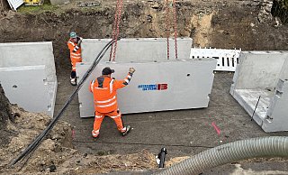 Arbeiter des Fachunternehmens setzen das in vorgefertigten Modulen angelieferte Material für den Gewässerdurchlass zusammen. - Stadt Lage
