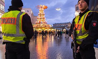 Schwer bewaffnete Polizisten mit Maschinenpistolen sichern die begehbare Pyramide auf dem Weihnachtsmarkt in Hannover. - Foto: Julian Stratenschulte/dpa