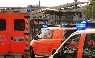 Rettungsfahrzeuge der Feuerwehr stehen mit Blaulicht vor dem Bahnhof am D&uuml;sseldorfer Flughafen. Wegen Klimaanlagen-St&ouml;rungen in zwei Regionalz&uuml;gen rief die Bahn die Rettungskr&auml;fte. - Foto: David Young