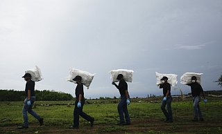 Polizisten tragen S&auml;cke mit beschlagnahmten Drogen, die w&auml;hrend einer Entsorgungsaktion an der M&uuml;ndung des Bayano River in Panama zerst&ouml;rt werden sollen. Insgesamt wurden mehrere Tonnen Kokain, Marihuana und synthetische Drogen vernichtet. - Foto: Arnulfo Franco/AP/dpa