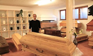 Gernot Begemann im Ausstellungsraum. Hier können verschiedene Modelle angeschaut werden. Im Vordergrund ein heller Eichensarg, der komplett in der Schwalenberger Firma hergestellt wurde. - Freya Köhring