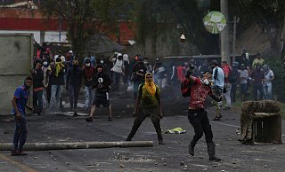 Vermummte Anti-Regierungs-Demonstranten werfen in Gachancipa Steine auf die Sicherheitskräfte während anhaltender Proteste. - Foto: Ivan Valencia/AP/dpa