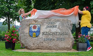 Künstlerin Anja Meier-Schirra (links) und Maren Becker von der Dorfgemeinschaft Rischenau enthüllen den Jubiläumsstein. - Raphael Bartling Künstlerin Anja Meier-Schirra (links) und Maren Becker von der Dorfgemeinschaft Rischenau enthüllen den Jubiläumsstein. - Raphael Bartling