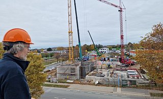 Matthias Rabe schaut vom Dach des Stadtwerke-Gebäudes am Liemer Weg auf die Baustelle auf der anderen Straßenseite. Im unteren Bereich ensteht das Anlagengebäude, weiter oben ist schon das runde Fundament (rot und schwarz) für den Wärmespeicher zu sehen. - Nadine Uphoff