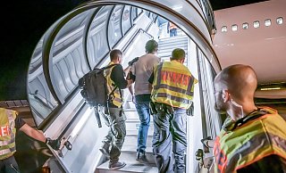 Abschiebung: Polizeibeamte begleiten einen Afghanen auf dem Flughafen Leipzig-Halle in ein Charterflugzeug. - Foto: Michael Kappeler/dpa