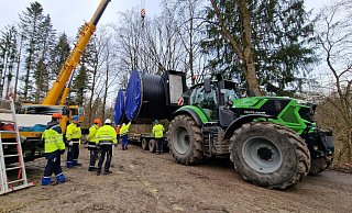 Die Schieberkammer des neuen Trinkwasserhochbehälters in Lüerdissen wird per Kran direkt neben den Försterteichen auf einen Traktor umgeladen, der ihn den Berg hochziehen wird. - Nadine Uphoff